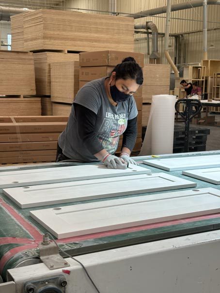 A Cabo worker hand finishing cabinet doors on the factory floor